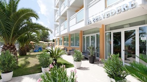 Un hotel con diseño moderno, que cuenta con un espacio exterior cuidado con plantas en macetas y una zona de juegos infantiles.