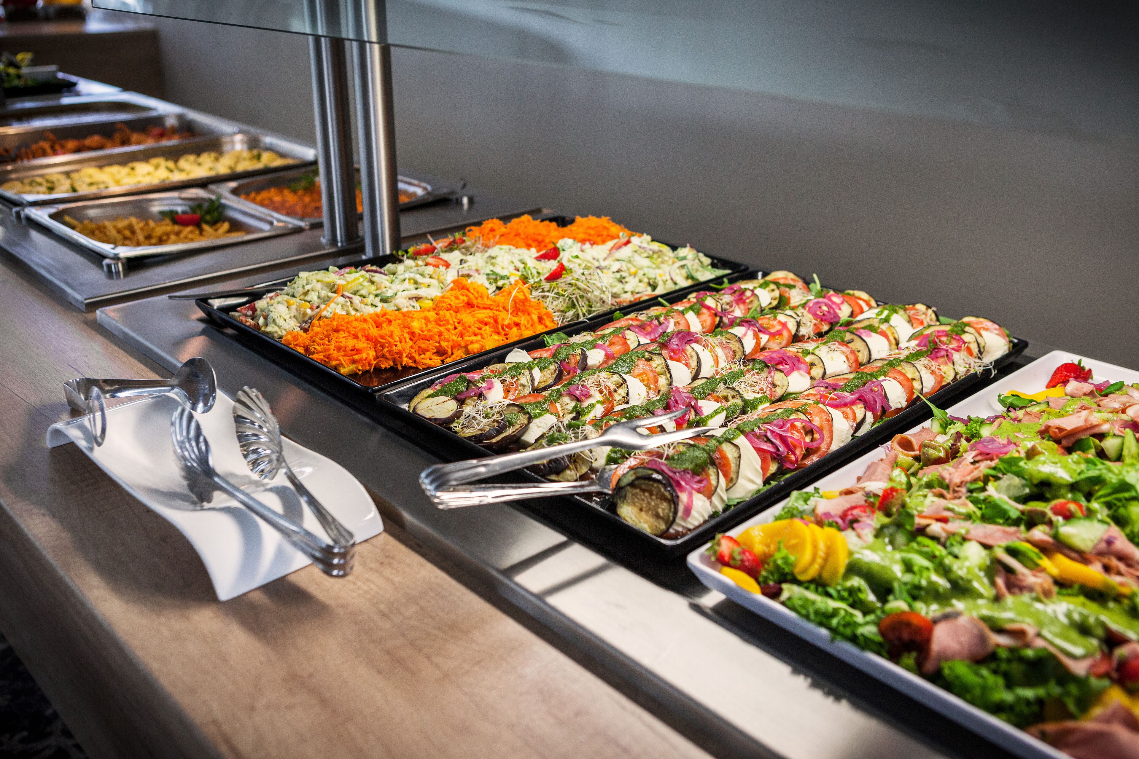 Een buffet met diverse gerechten, waaronder salades, belegde broodjes en andere bereide maaltijden.