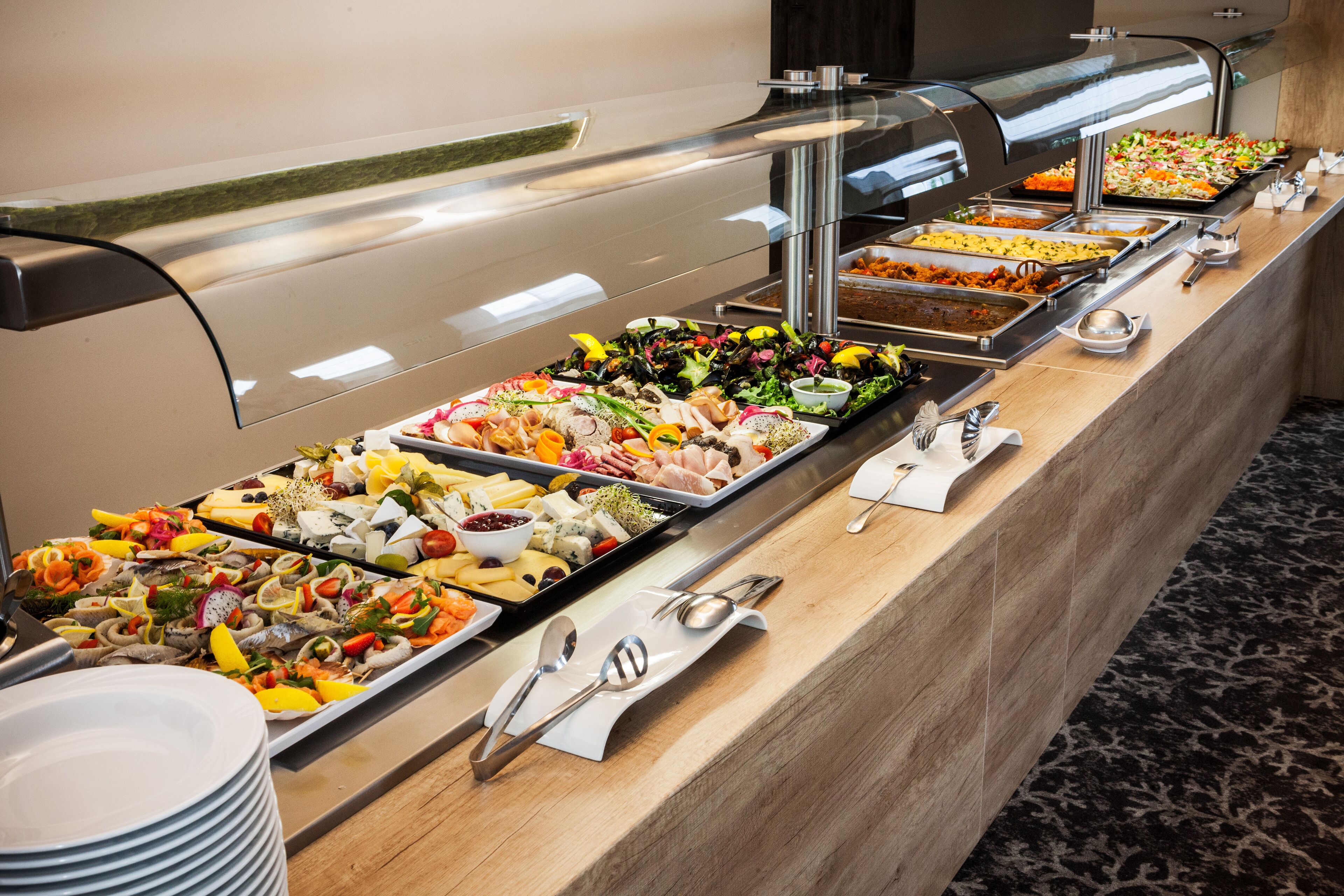 A buffet with various food items and utensils.