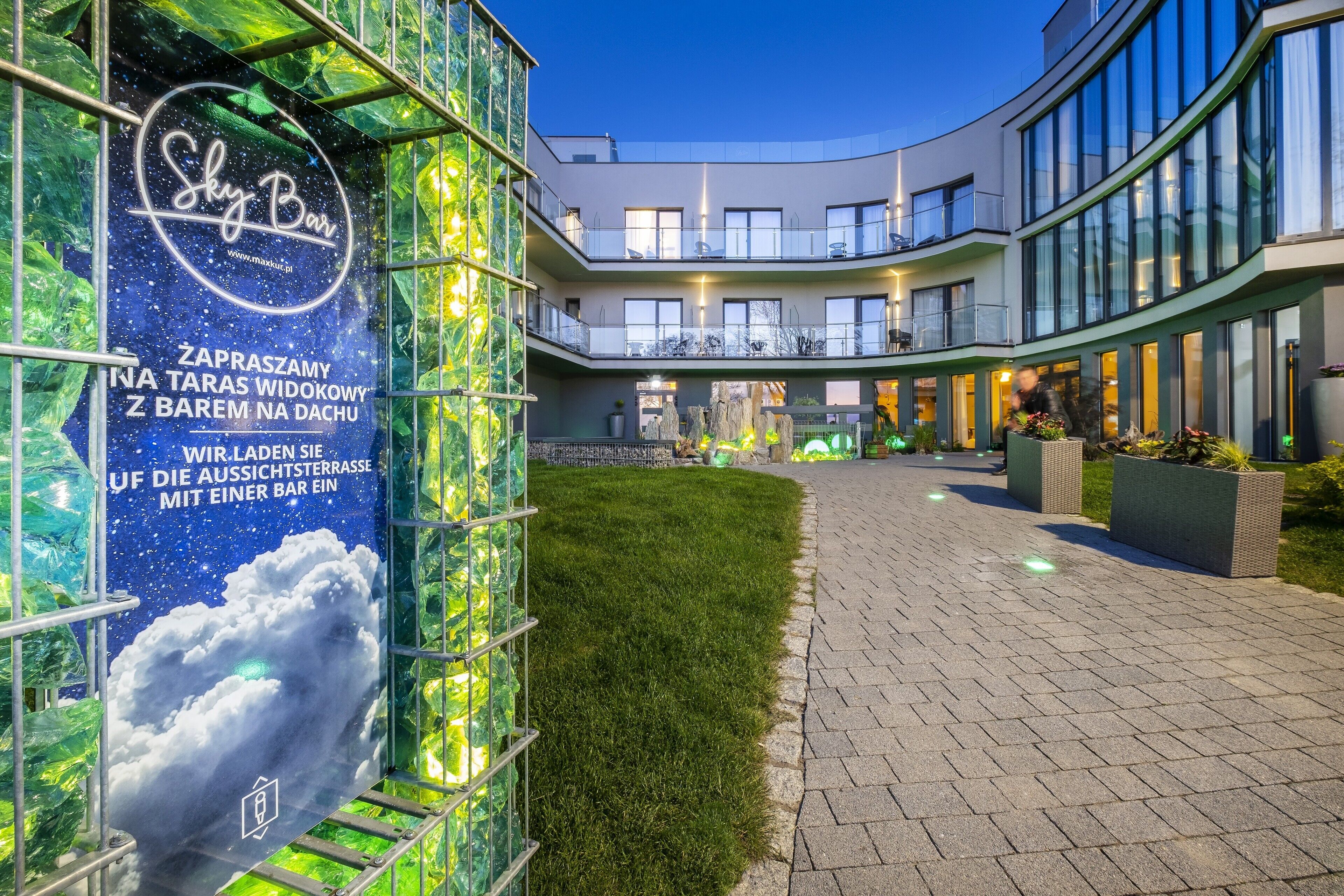 Un bâtiment moderne, avec une enseigne « Sky Bar », une pelouse bien entretenue et un chemin piétonnier dallé.