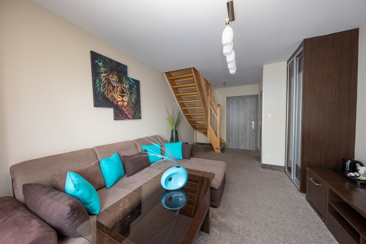 A living room with a sofa, a coffee table, a painting, a staircase, and a cabinet.