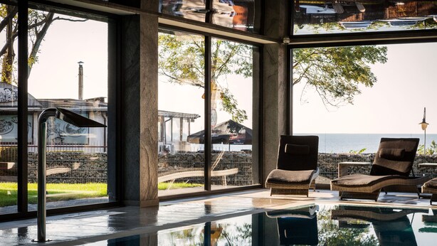 A modern interior with a glass pool, lounge chairs, and a view of the sea. - Max Health Resort SPA (Ustronie Morskie)