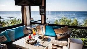 A cozy seating area with a view of the ocean, a table with a drink and a salad, and a sign about life balance. - Max Health Resort SPA (Ustronie Morskie)
