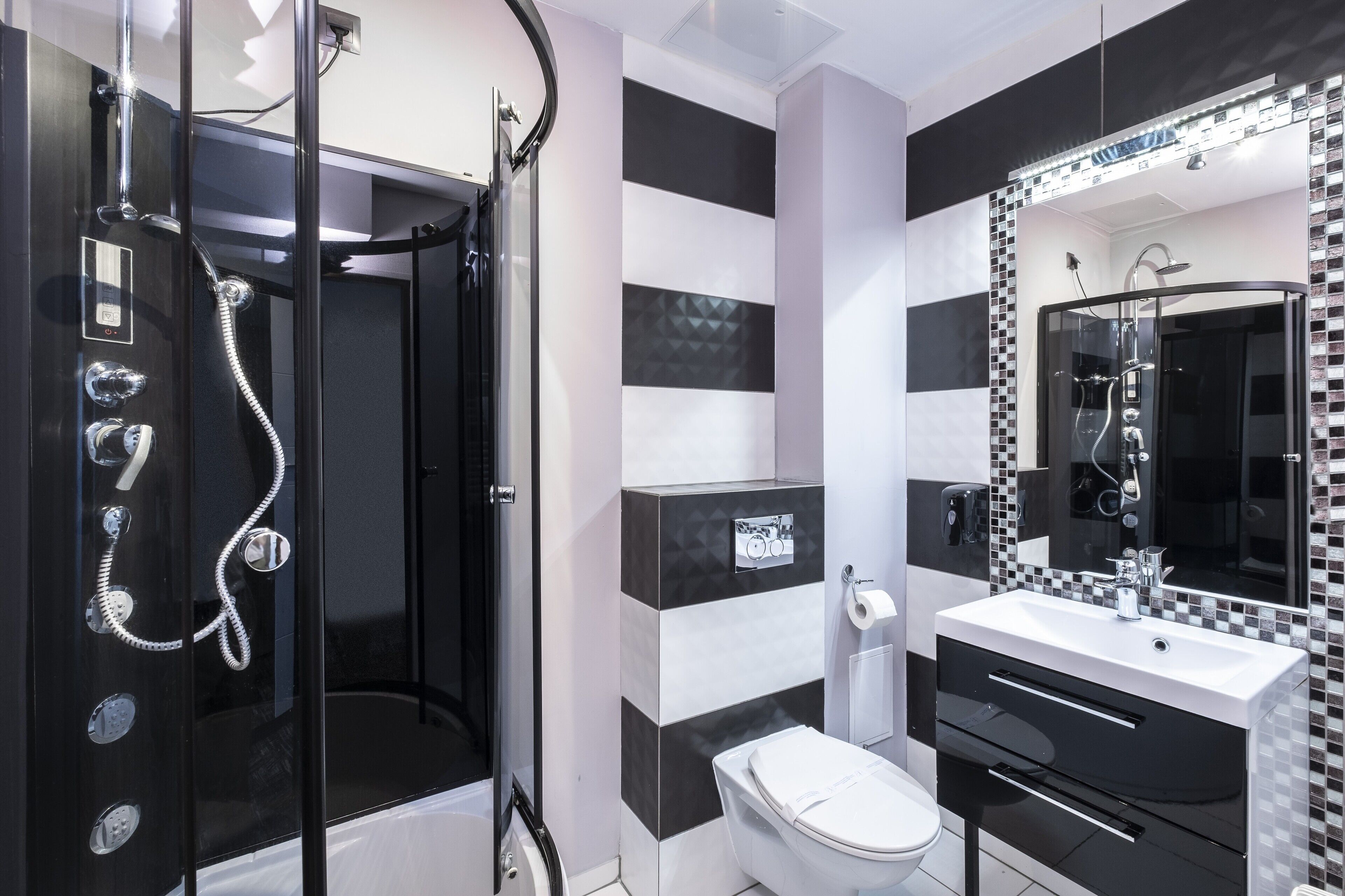 Un baño moderno con ducha envuelta en vidrio, inodoro blanco y tocador con espejo.