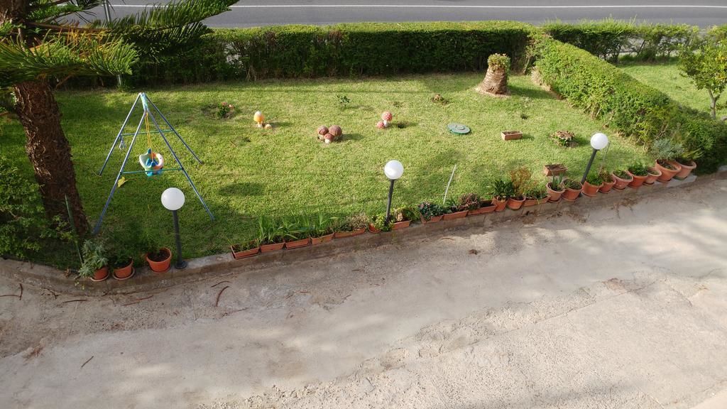 Ein gepflegter Garten mit Schaukel, Blumentöpfen und einem gepflasterten Weg.
