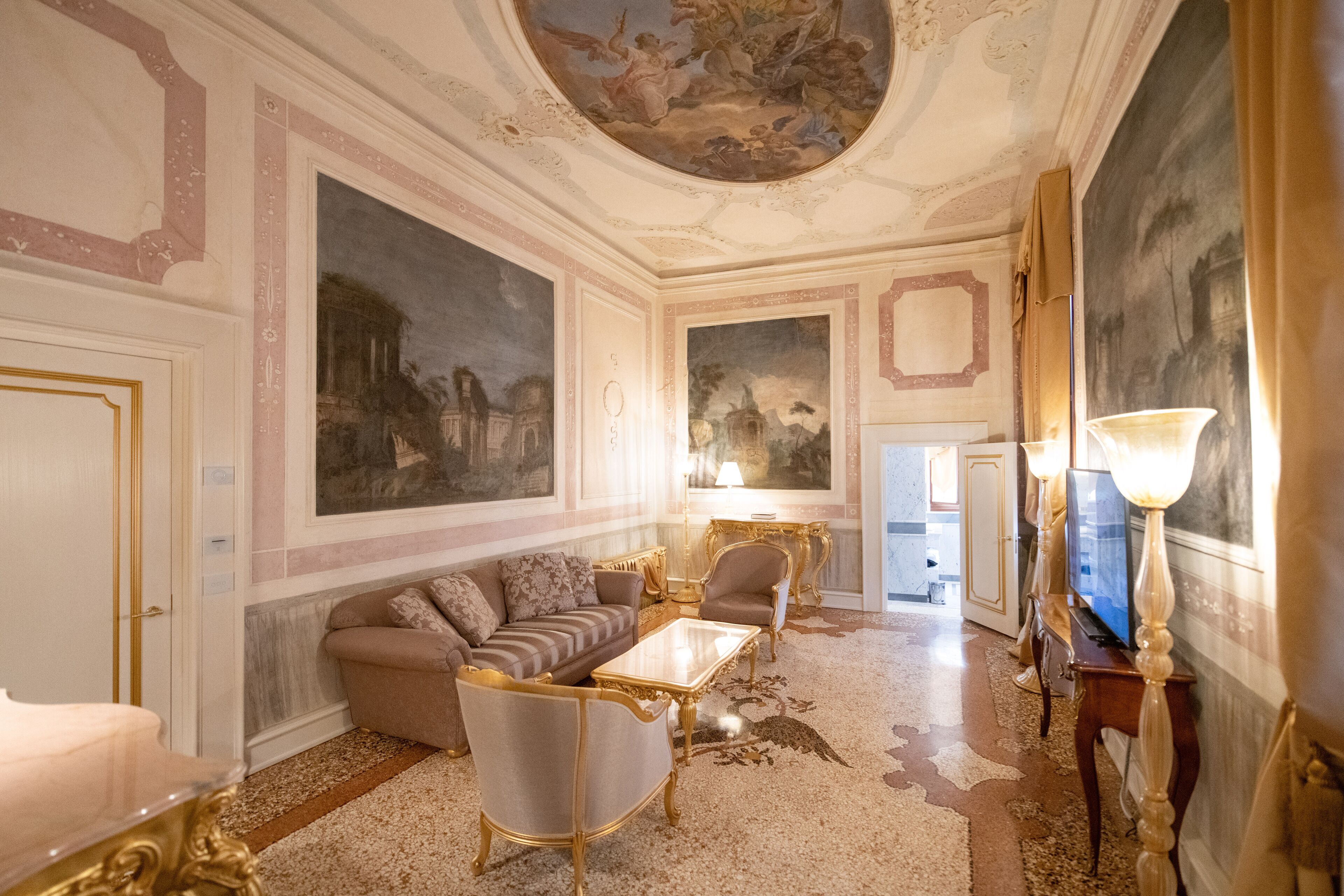 Ein luxuriöses Zimmer mit einer großen Couch, Sesseln, einem Couchtisch und einem Fernseher.