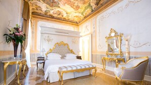 Un dormitorio lujoso con una cama grande, muebles dorados ornamentados y un techo decorativo.