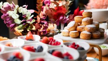 A buffet table with a variety of food items including pastries and fresh fruits.