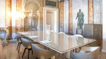 Uma sala de conferências com uma mesa de vidro, seis cadeiras e estátuas clássicas.