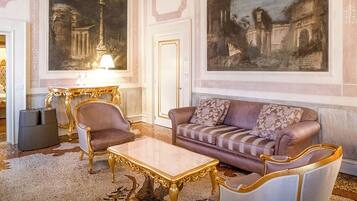 Eine luxuriöse Lobby mit einem Marmortisch, eleganten Sesseln, einer komfortablen Couch und großen, klassischen Gemälden an den Wänden.