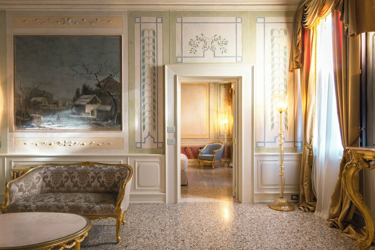 A room with a large painting, a sofa, a table, and a chair.