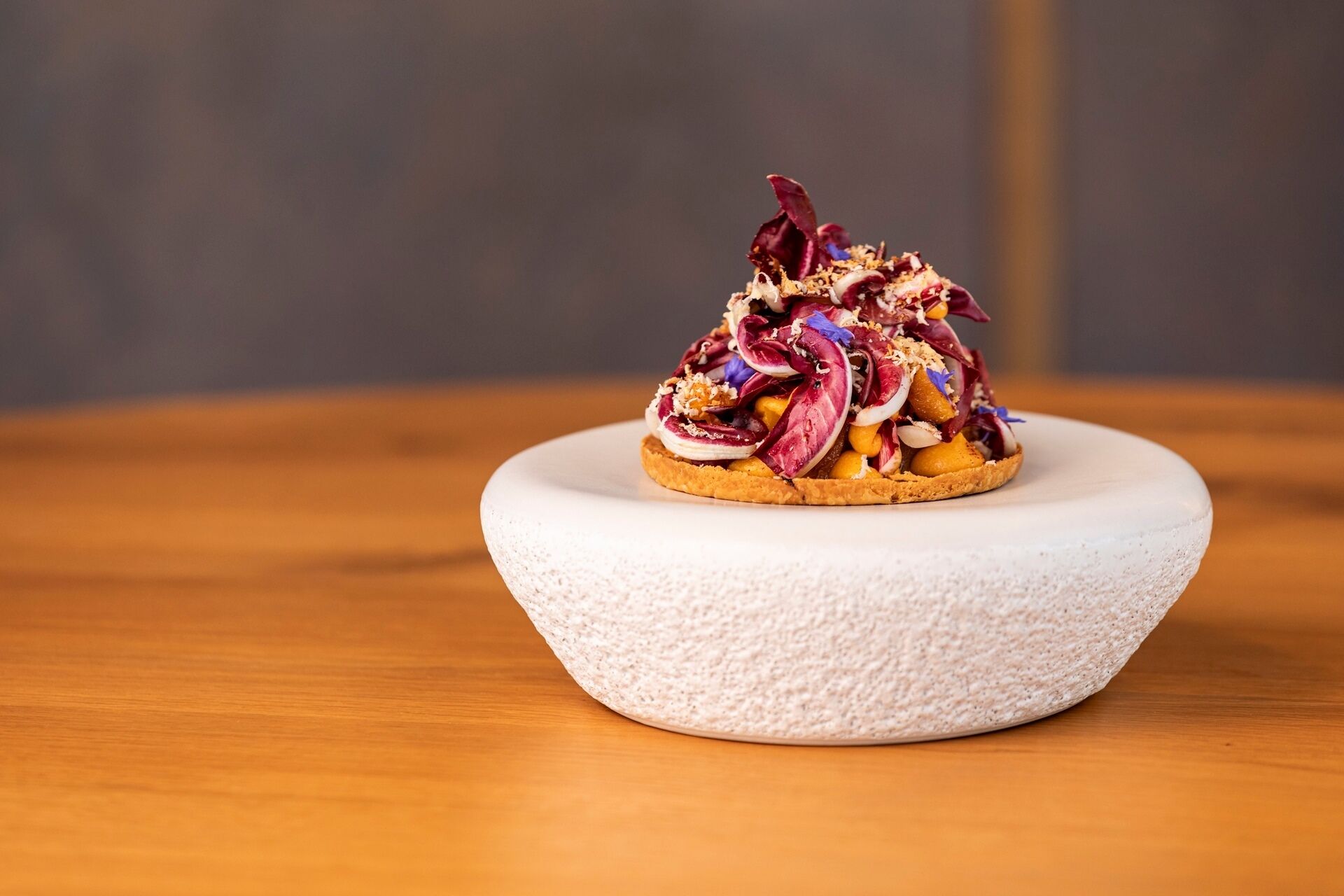 A dish on a white textured plate on a wooden table.