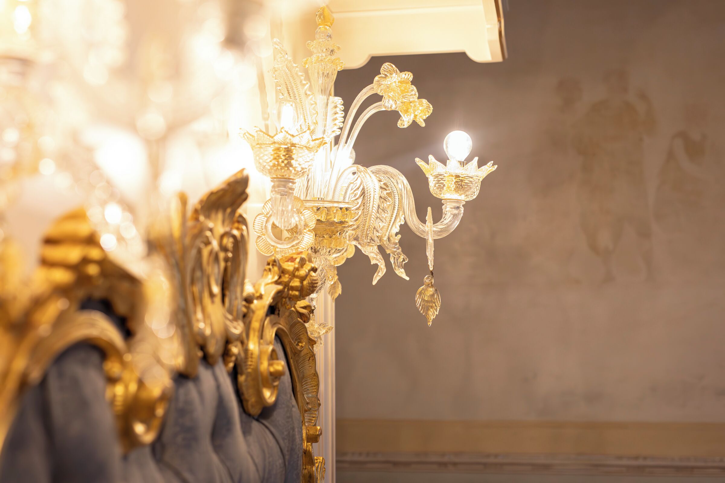 Un lustre orné de motifs complexes en or et doté de nombreuses ampoules.