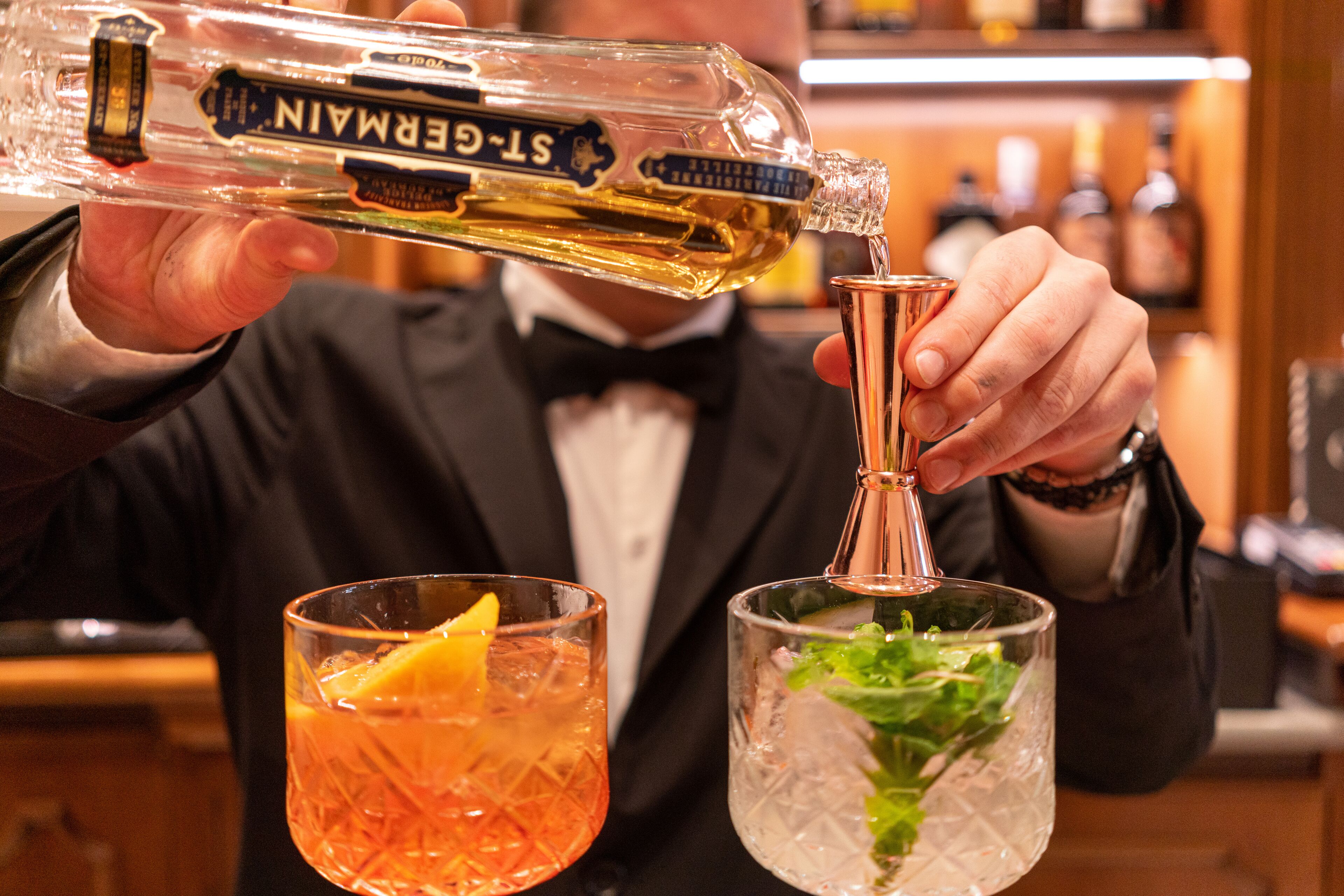 Een barman giet een drankje inschenken uit een fles in een glas.