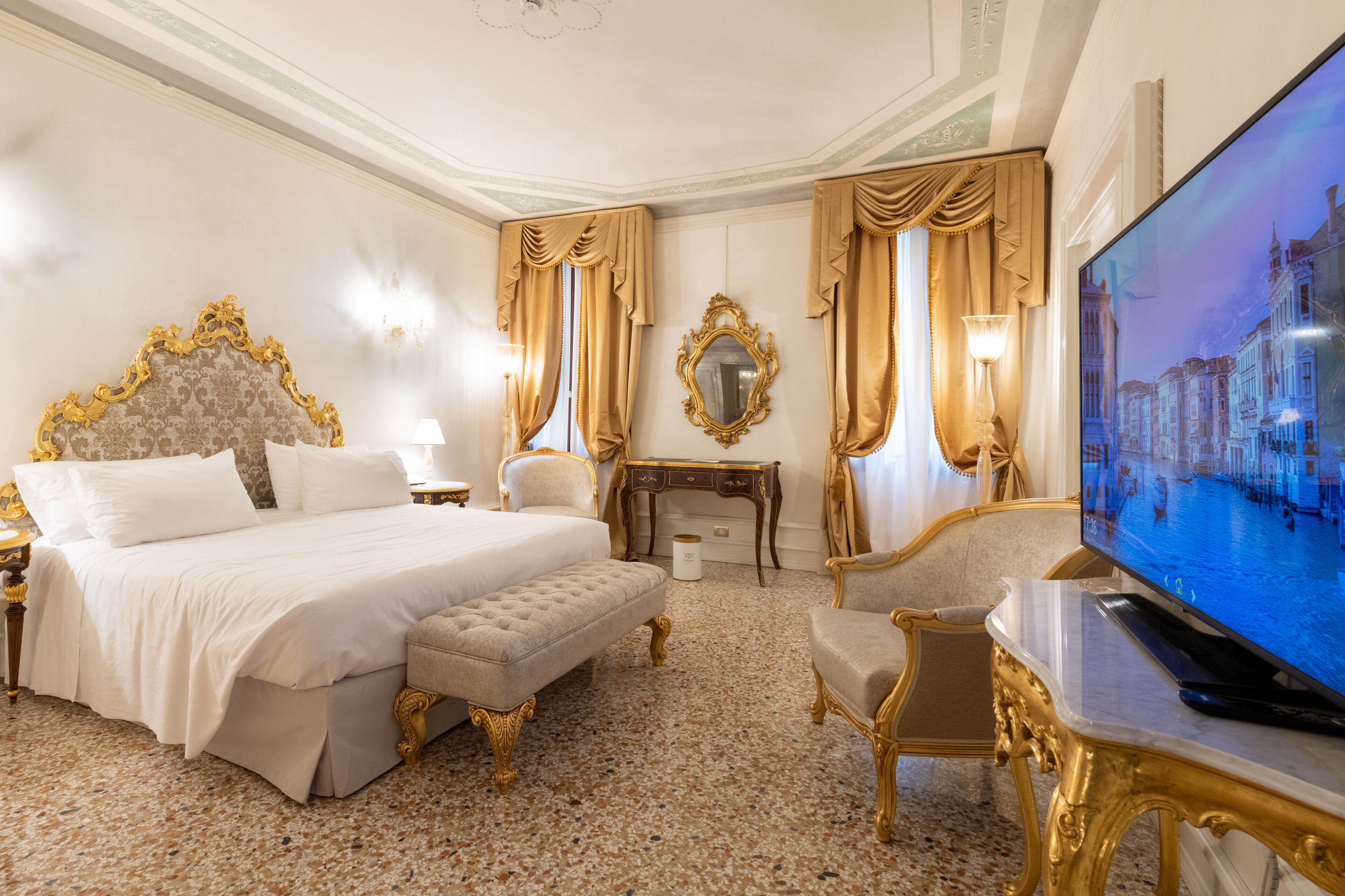 Una lussuosa camera d'albergo con un ampio letto, una televisione, una scrivania e una poltrona.