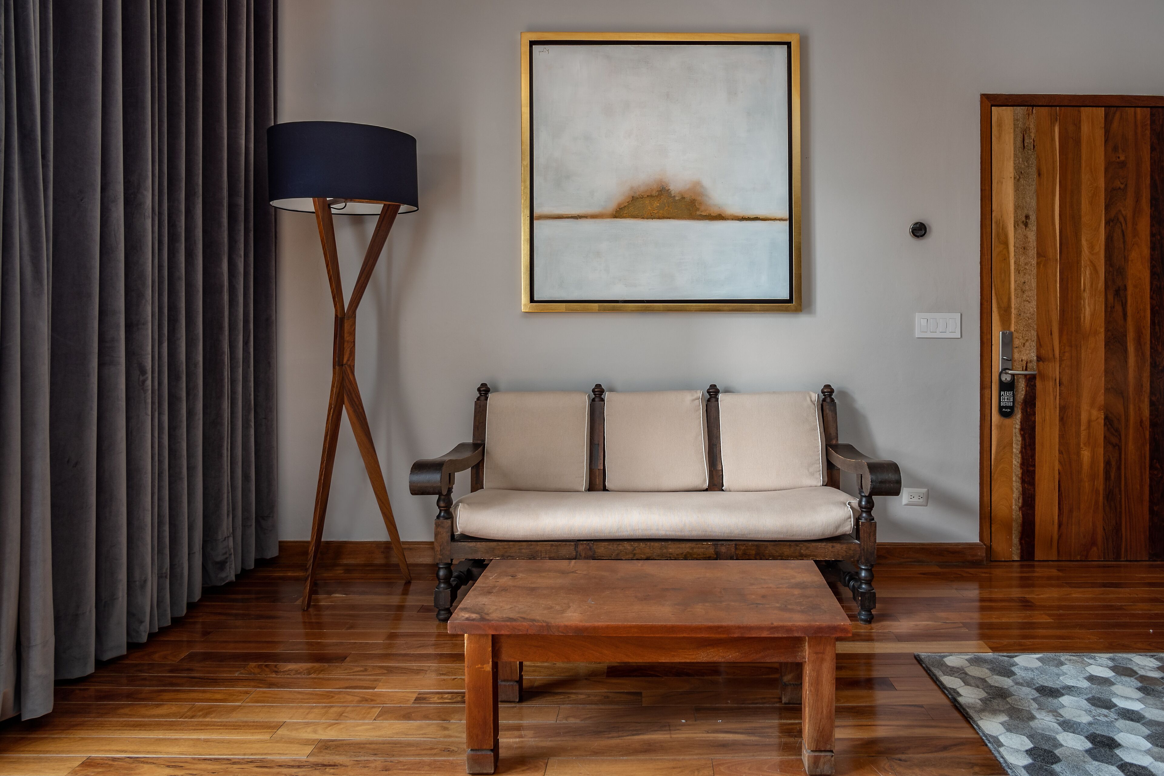 Una habitación con piso de madera, un sofá, una mesa de centro, una lámpara y una puerta.