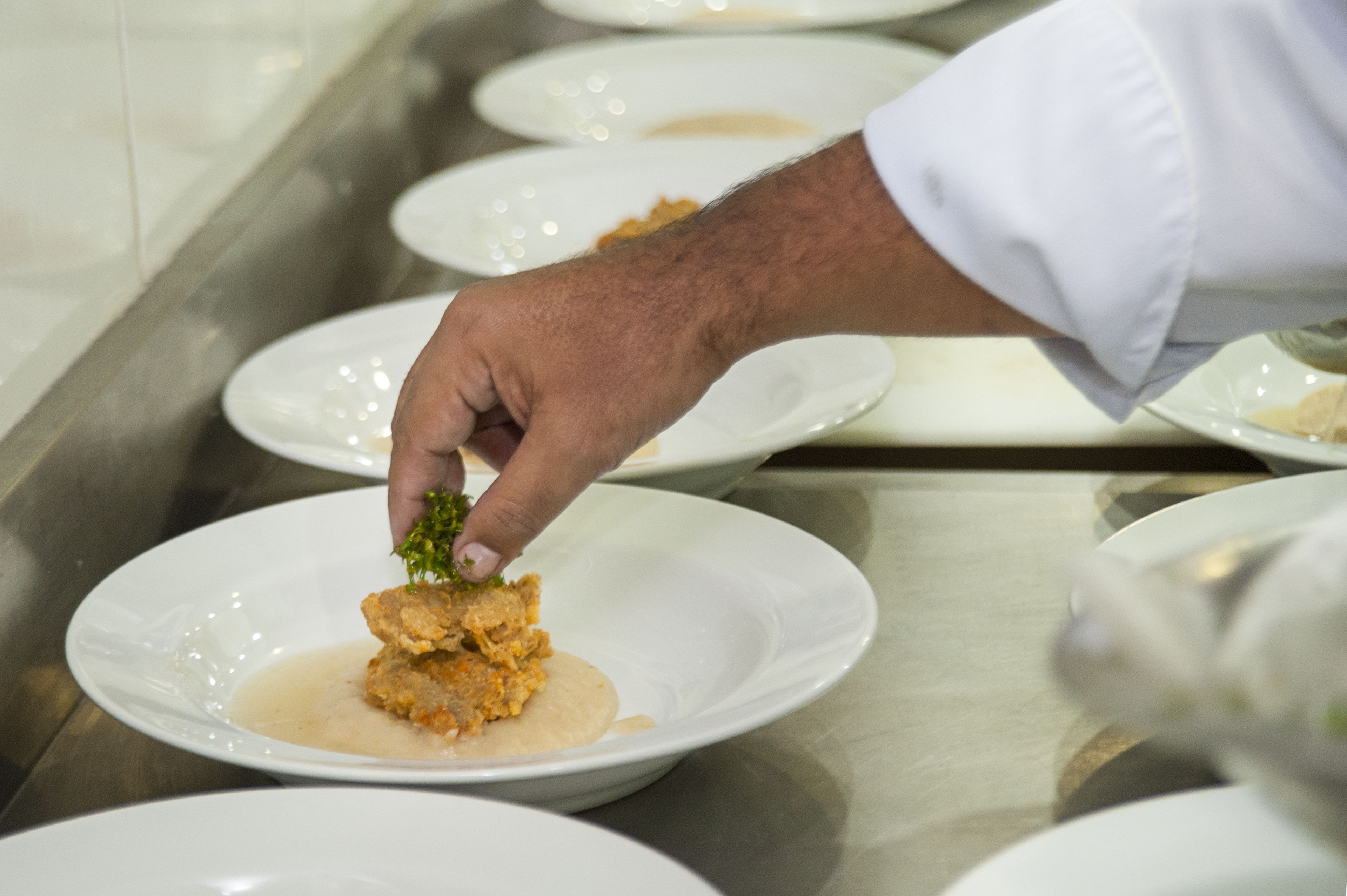 A hand placing a food item on a plate.