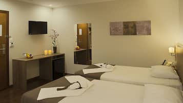 Quarto de hotel com duas camas, uma escrivaninha, uma televisão e um espelho.
