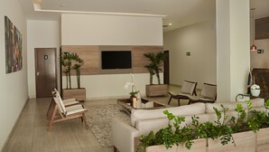 Eine moderne Lobby mit einer Couch, Sesseln, einem Couchtisch und Topfpflanzen.