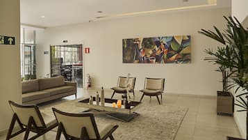 Un vestíbulo moderno con un sofá, sillas, una mesa de centro y un cuadro abstracto grande.