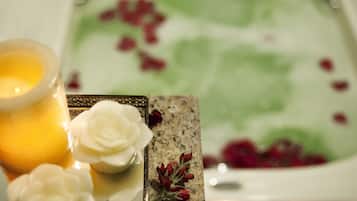 A candle, a decorative plate with flowers, and a glass of water.
