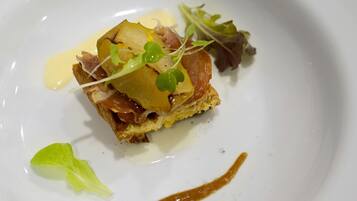 A dish with a piece of bread topped with meat, vegetables, and a sauce on a white plate.