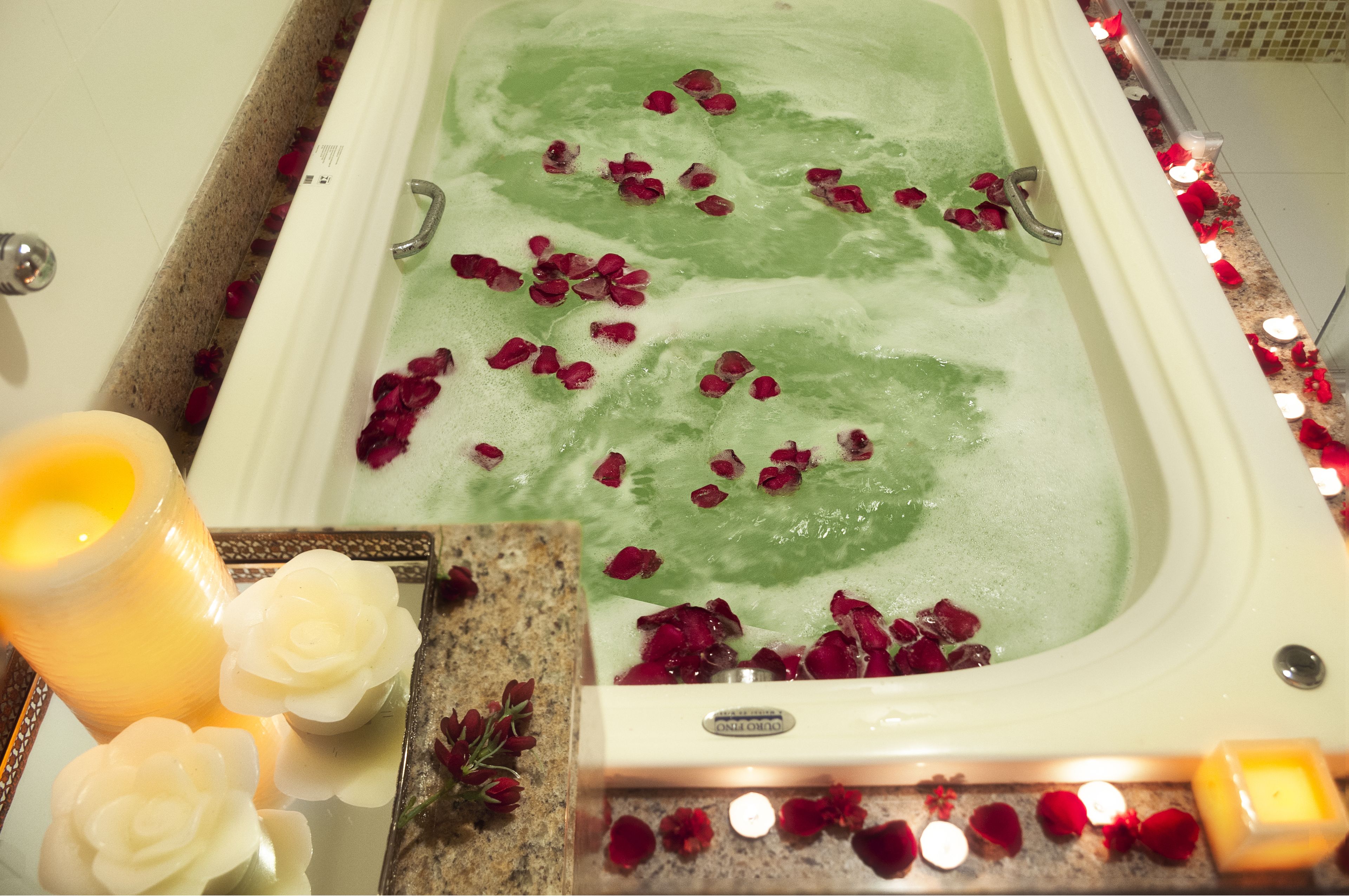 A bathtub with rose petals and candles, suggesting a spa setting.