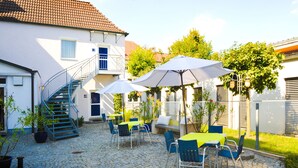 A courtyard with outdoor seating, a staircase, and a building with a tiled roof. - Hotel Purucker (Kulmbach)