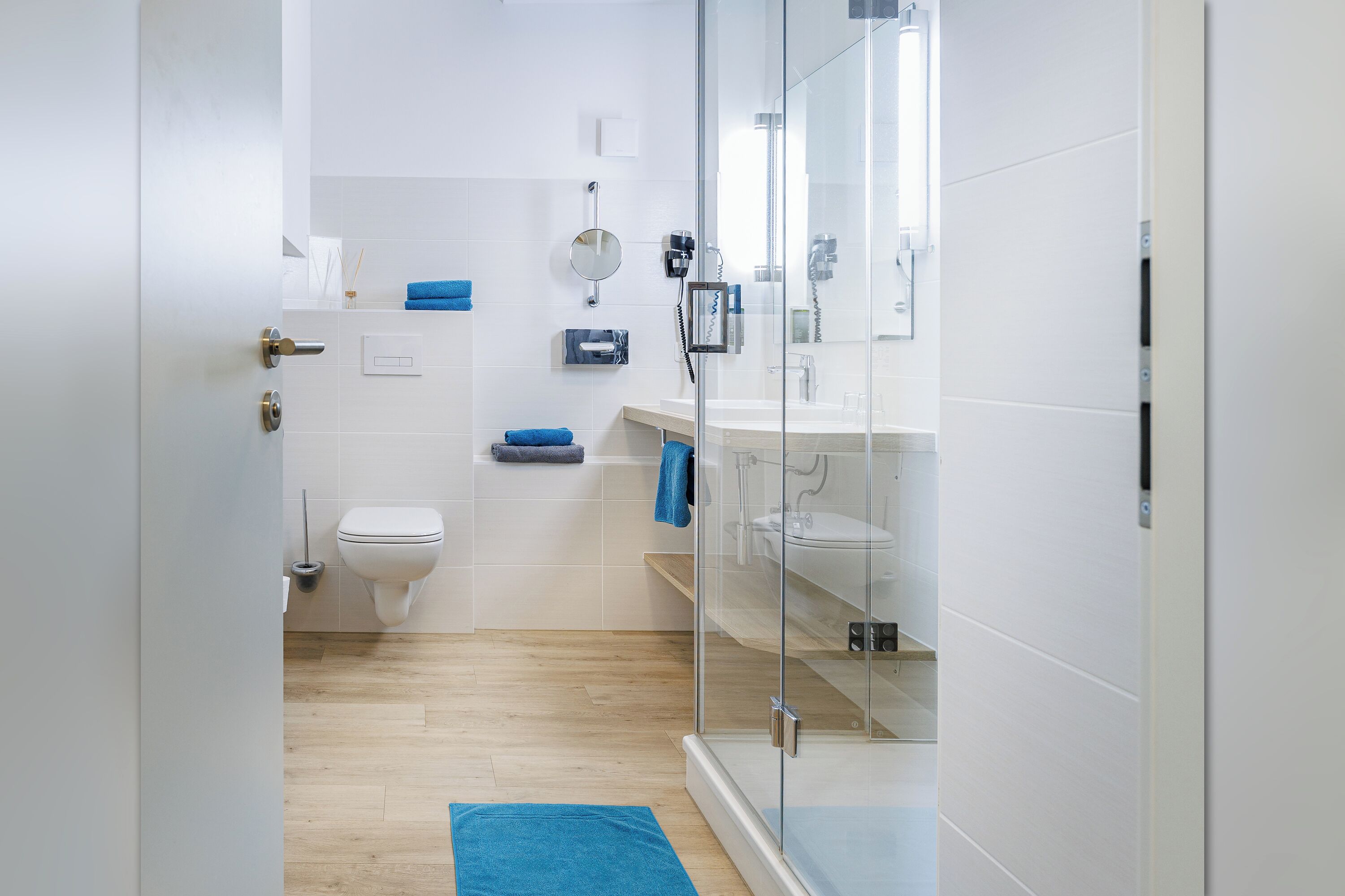 Un bagno moderno con box doccia in vetro, un water e un lavandino.