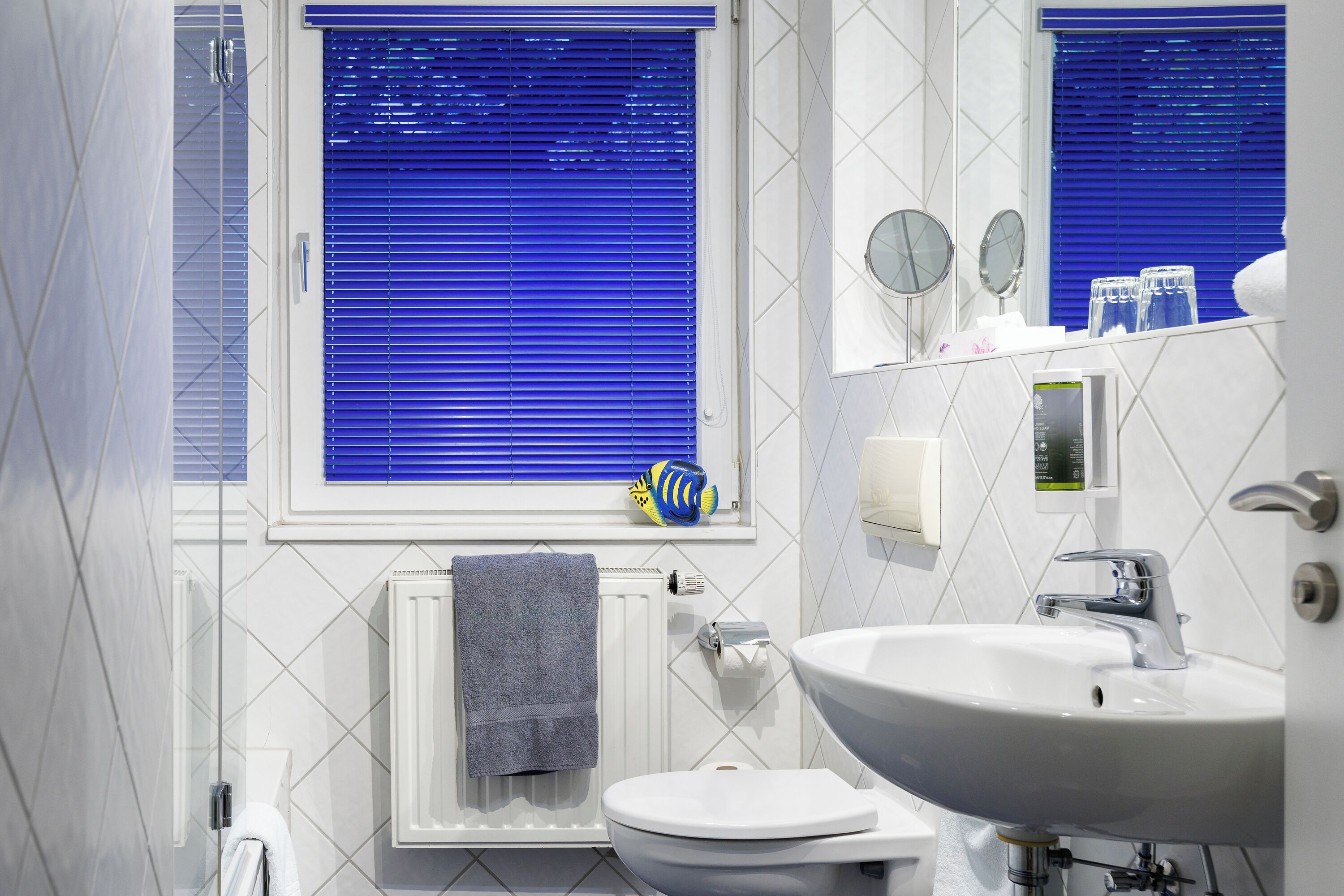 Ein Badezimmer mit Toilette, Waschbecken und Fenster mit Jalousien.