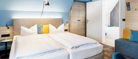 Una habitación de hotel moderna con una cama grande, un escritorio, una silla y un armario.