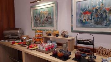 Un bufé de desayuno con diversas opciones de comida y bebidas, obras de arte enmarcadas en las paredes y una máquina de café.