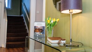 A staircase with a glass railing, a welcome sign, a vase with tulips, a lamp, and a book on a table. - Rooms at 31 (Stonehaven)