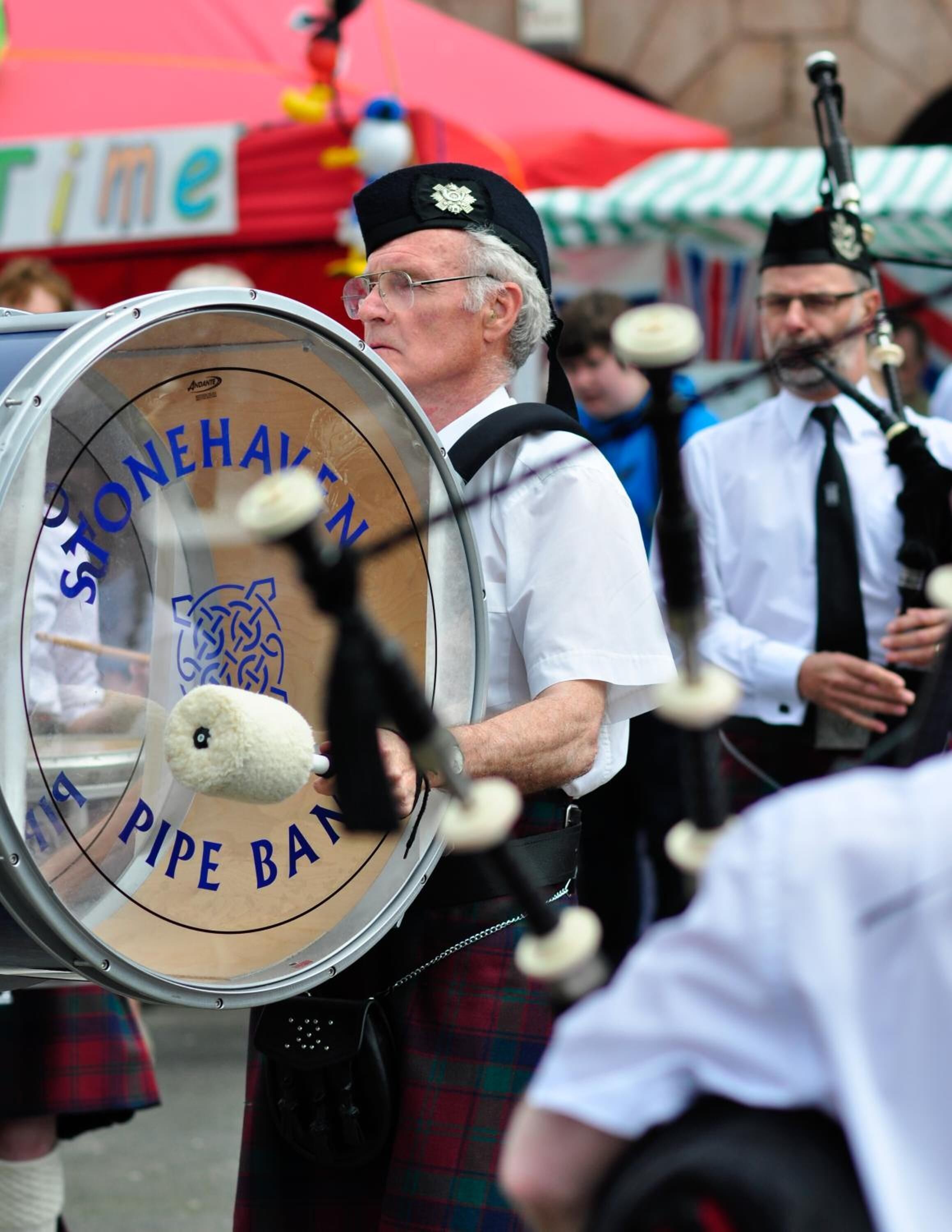 Uma pessoa tocando bateria, com um logotipo que diz 'STONEHALL PIPE BAND'.
