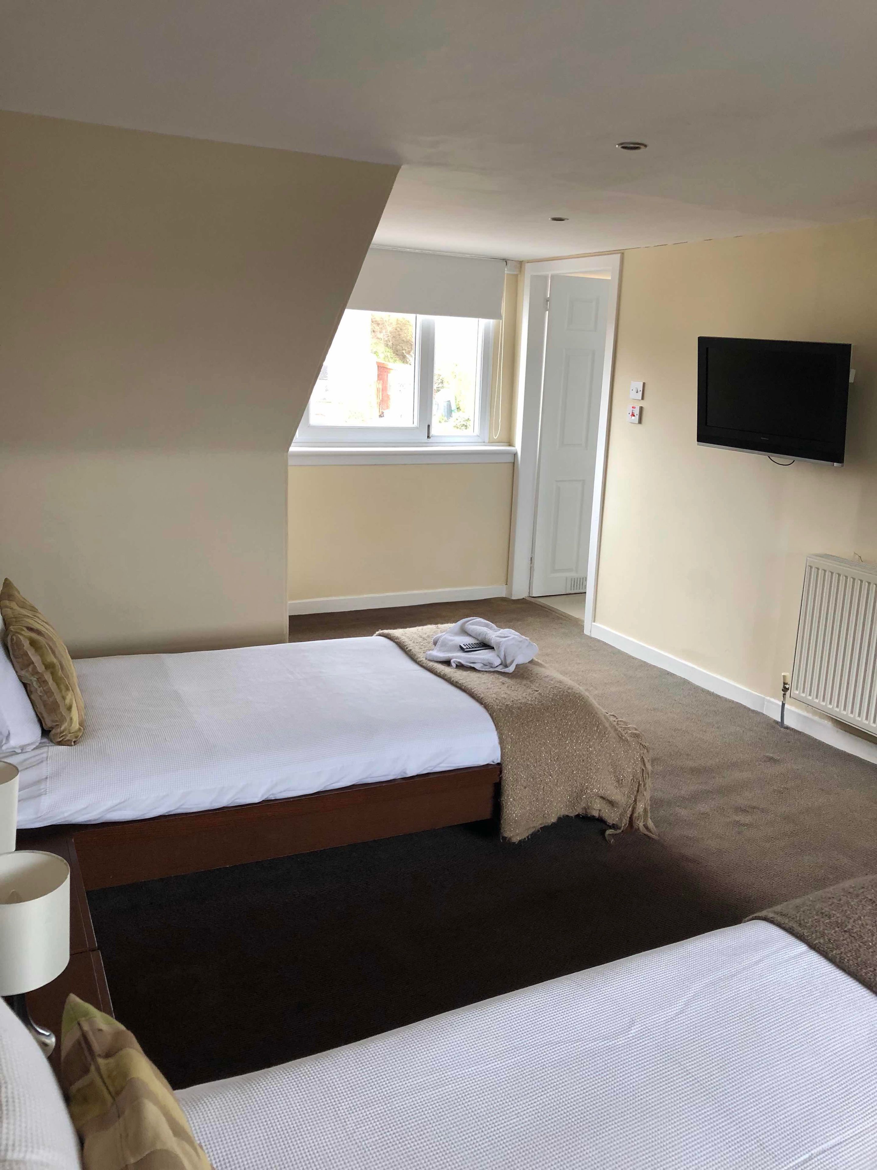 A hotel room with two beds, a television, and a window.