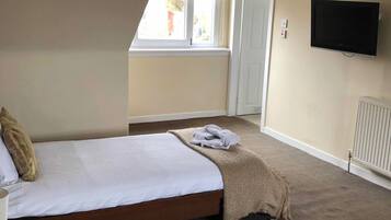A hotel room with two beds, a television, and a window.