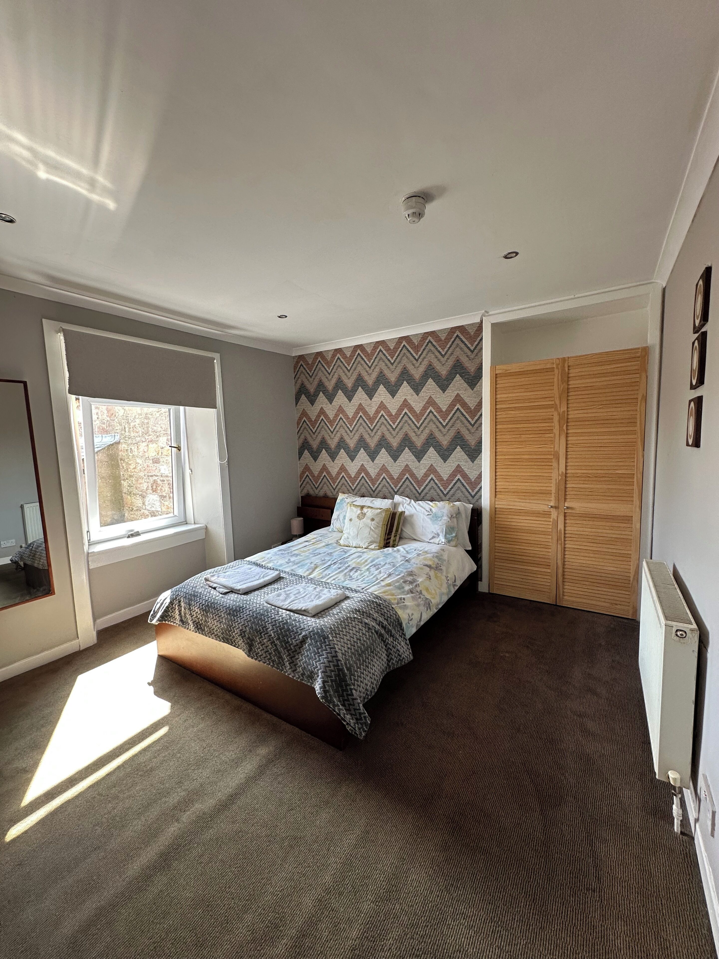 Een slaapkamer met een bed, een raam, een kast en een radiator.