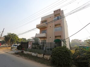 A multi-story residential building with balconies, a gated entrance, and a parked car. - OYO 11337 Asian Hospitality (Gurugram)
