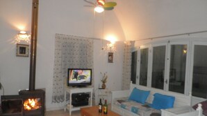 A cozy living room with a fireplace, a television, and a sofa. - Dar Tomoko & Salah (Raf Raf)