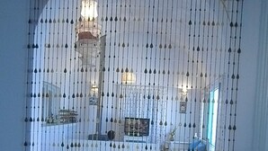 A room with a large arched window, a white sofa, and a chandelier. - Dar Tomoko & Salah (Raf Raf)