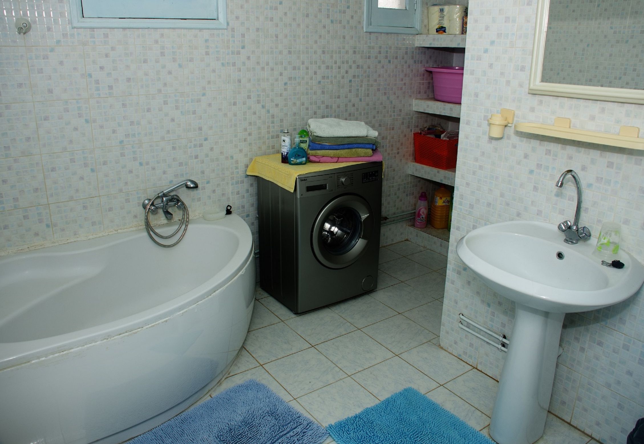 A bathroom with a bathtub, a washing machine, and a sink.