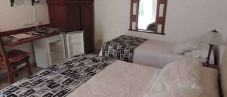 A bedroom with two beds, a desk, a chair, a television, and a mirror.
