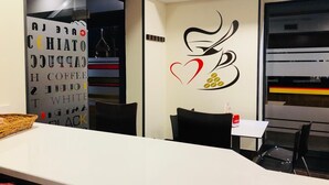 A modern interior with a wall featuring a coffee cup and heart design, a white table, and black chairs. - Hotel Viñas 17 (Teruel)