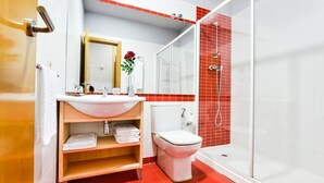 A bathroom with a white sink, a toilet, and a glass-enclosed shower. - Hotel Viñas 17 (Teruel)