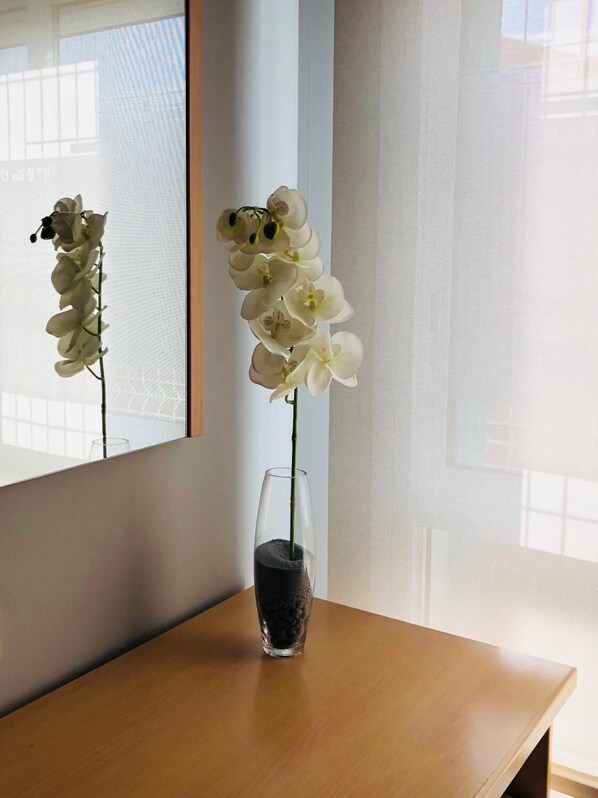 Una orquídea en solitario en un florero de vidrio transparente sobre una mesa de madera.