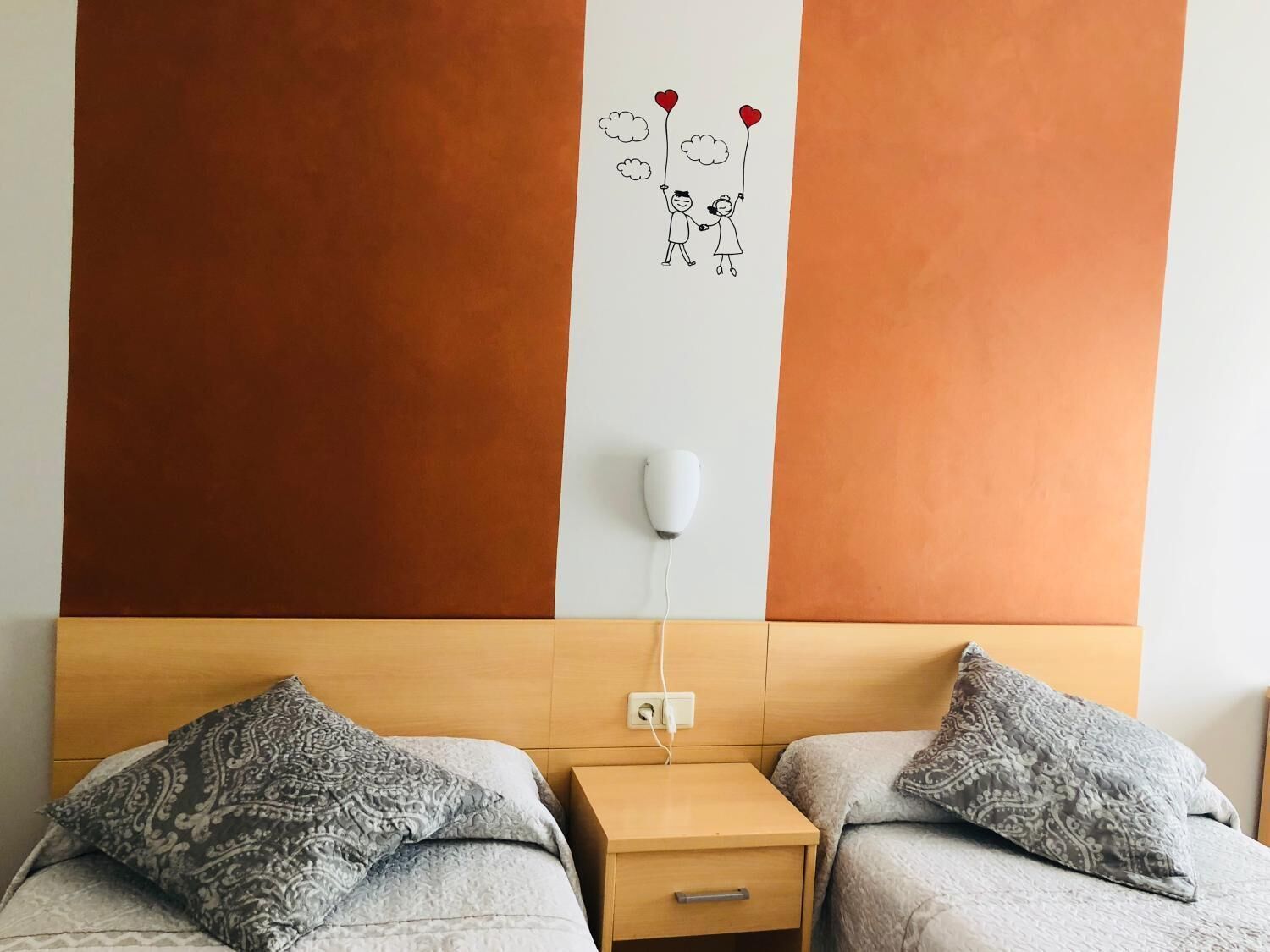 Un dormitorio con dos camas, cabeceros de madera, una mesita de noche y un adorno en la pared.