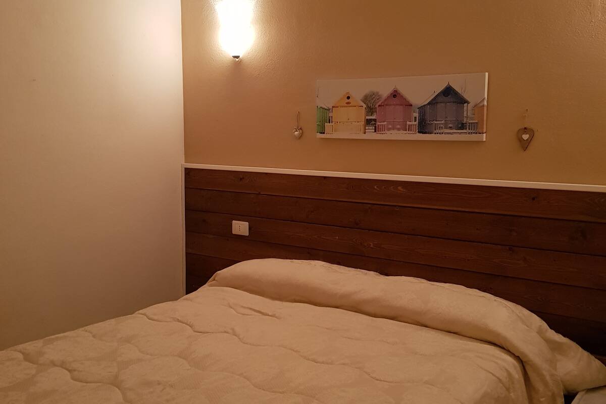 A bedroom with a wooden headboard, a white bedspread, and a small bedside table.