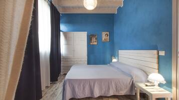 A bedroom with a bed, a nightstand, a lamp, and a wall with two pictures.
