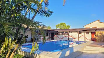 Una piscina al aire libre, sillones reclinables de piscina