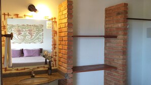 A bathroom with a sink, mirror, and a brick accent wall. - Pousada Coral de Fogo (Prado)